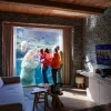 Une famille face à la baie vitrée d'une chambre de la White Bear House, avec un ours blanc juste derrière la vitre, à Pairi Daiza