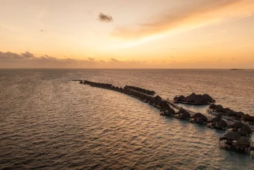 Vue aérienne au coucher du soleil des villas sur pilotis du Constance Halaveli Maldives, atoll d'Ari Nord