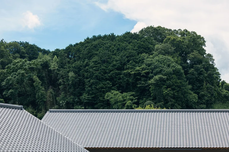 Salon d'une suite du resort Hoshinoya Asuka, canapé adossé à un rocher, claustras de bois et plafond haut