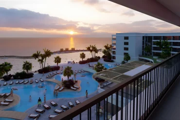 Rendu des piscines du resort The Pyrmont Curaçao, nouvel hôtel tout compris pour adultes, face à la mer des Caraïbes au coucher du soleil, à Willemstad