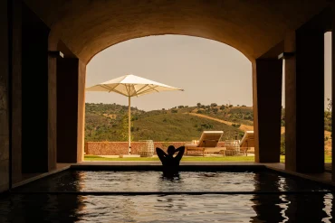 Bassin intérieur du spa de Viceroy at Ombria Algarve ouvert sous une arche sur les collines de l'Algarve