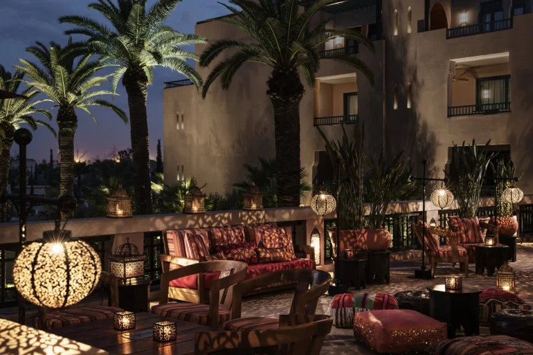 La terrasse du restaurant Inara au Four Seasons Resort Marrakech, salons et lanternes à la nuit tombée, sous les palmiers