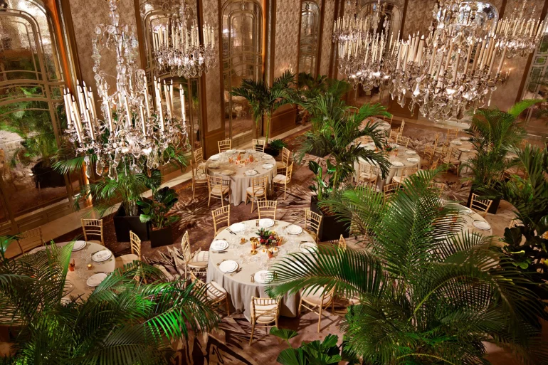 Le salon Haute Couture du Plaza Athénée, lustres de cristal, palmiers et tables rondes dressées pour un dîner