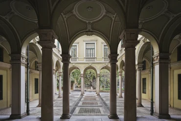 La cour à arcades et colonnes de pierre du palais du XIXe siècle qui accueillera le Rosewood Milan, ouverte sur un jardin