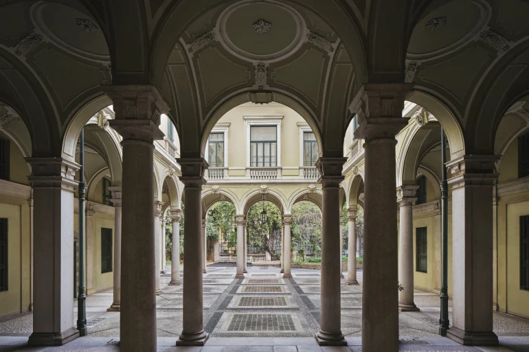 La cour à arcades et colonnes de pierre du palais du XIXe siècle qui accueillera le Rosewood Milan, ouverte sur un jardin
