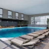Rendu 3D de la piscine intérieure chauffée du spa Naïora à Strasbourg, bordée de transats et de bambous