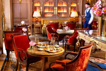 Le Salon Proust du Ritz Paris, fauteuils de velours rouge, bibliothèque éclairée et table dressée pour le tea time
