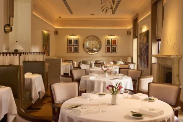 La salle du restaurant The Penn à Stoke Park, tables nappées de blanc et décor signé Studio Shayne Brady