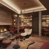 Le lounge de l'hôtel The Ski Lodge à Verbier, cheminée, bibliothèque et banquettes rouges, visuel de présentation